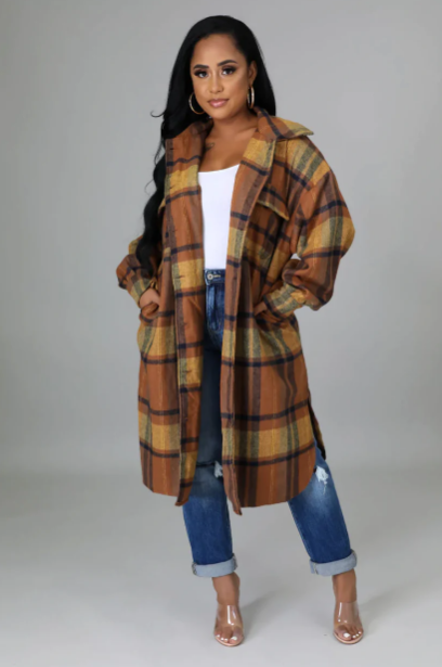 A woman wearing a long checkered coat over a white top and blue jeans. 